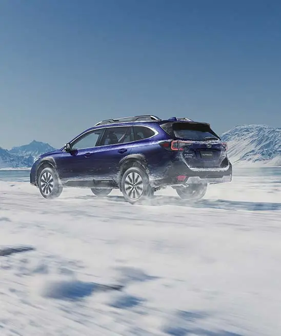 Saphire blue pearl Subaru Outback driving in snow